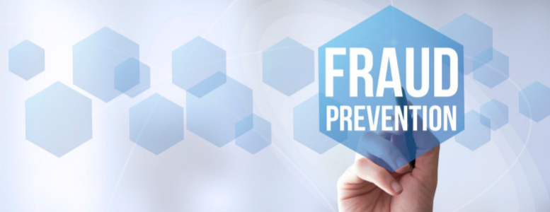 Hand writing with a pen, with text reading, "Fraud Prevention". The background includes may different sized transparent hexagons.